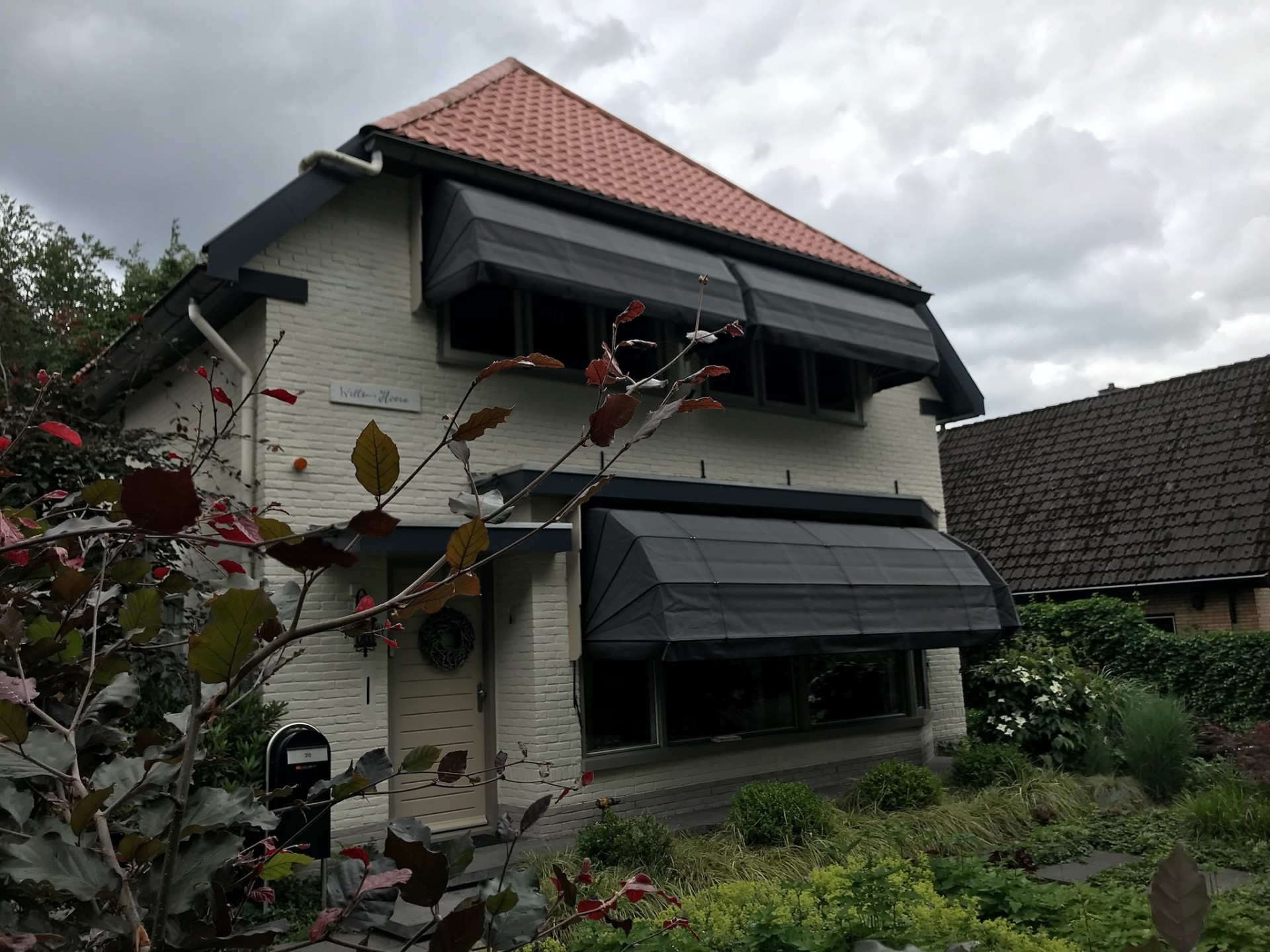 Witte villa met antraciet markiezen op meerdere verdiepingen