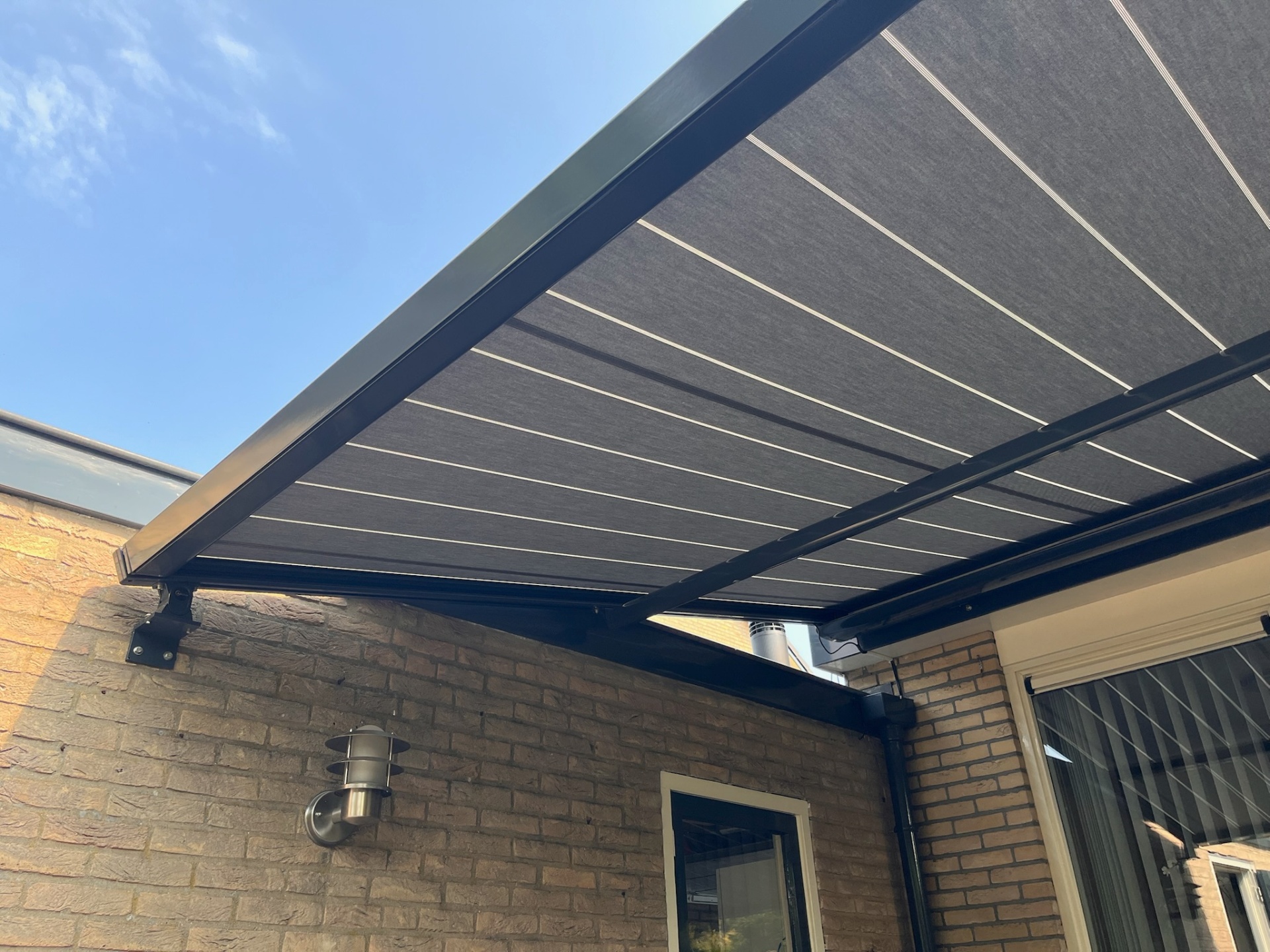 Detail van antraciet pergola met zwart frame en strakke baleinen
