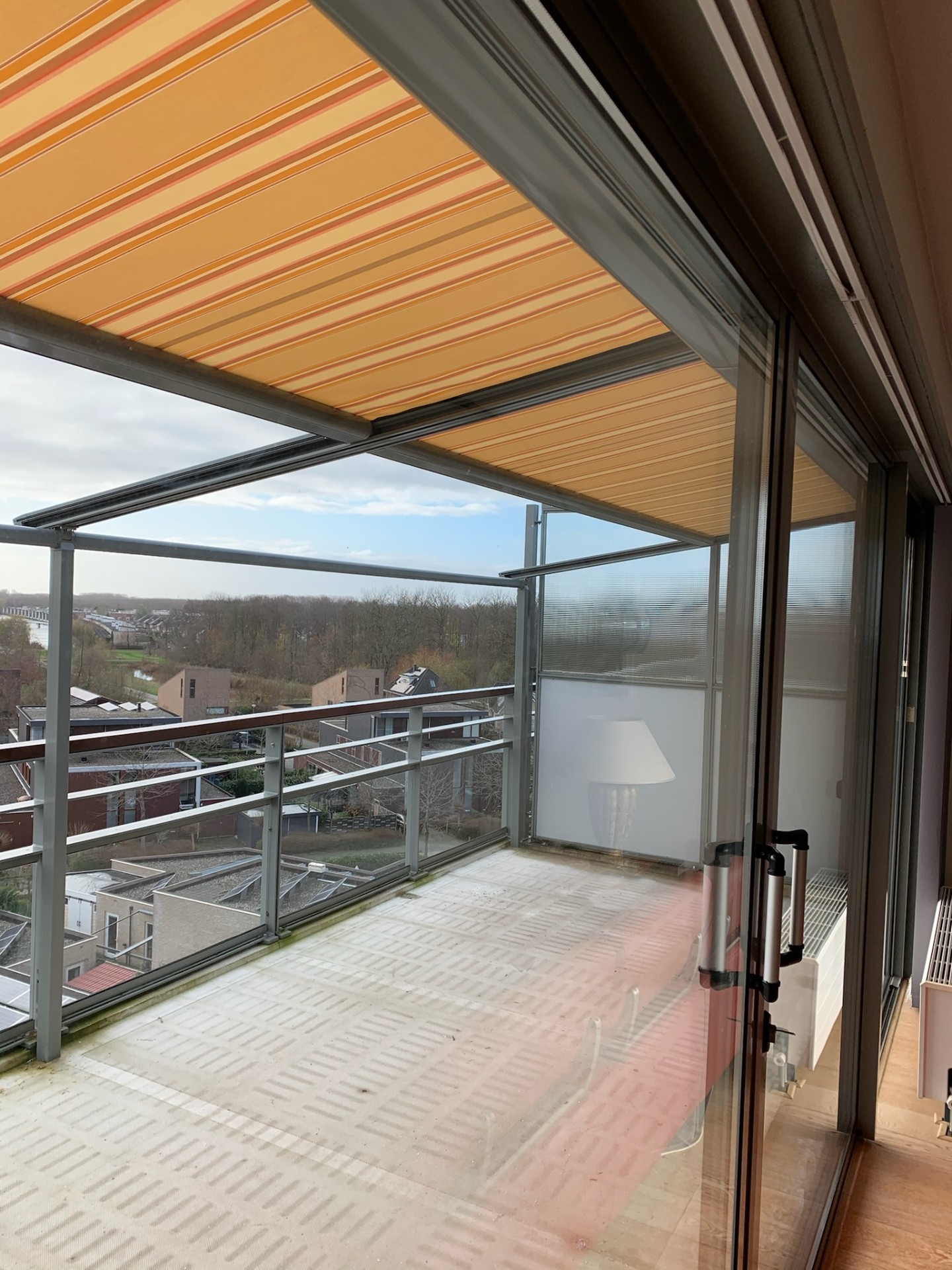 Pergola zonwering met oranje doek op appartement balkon met uitzicht
