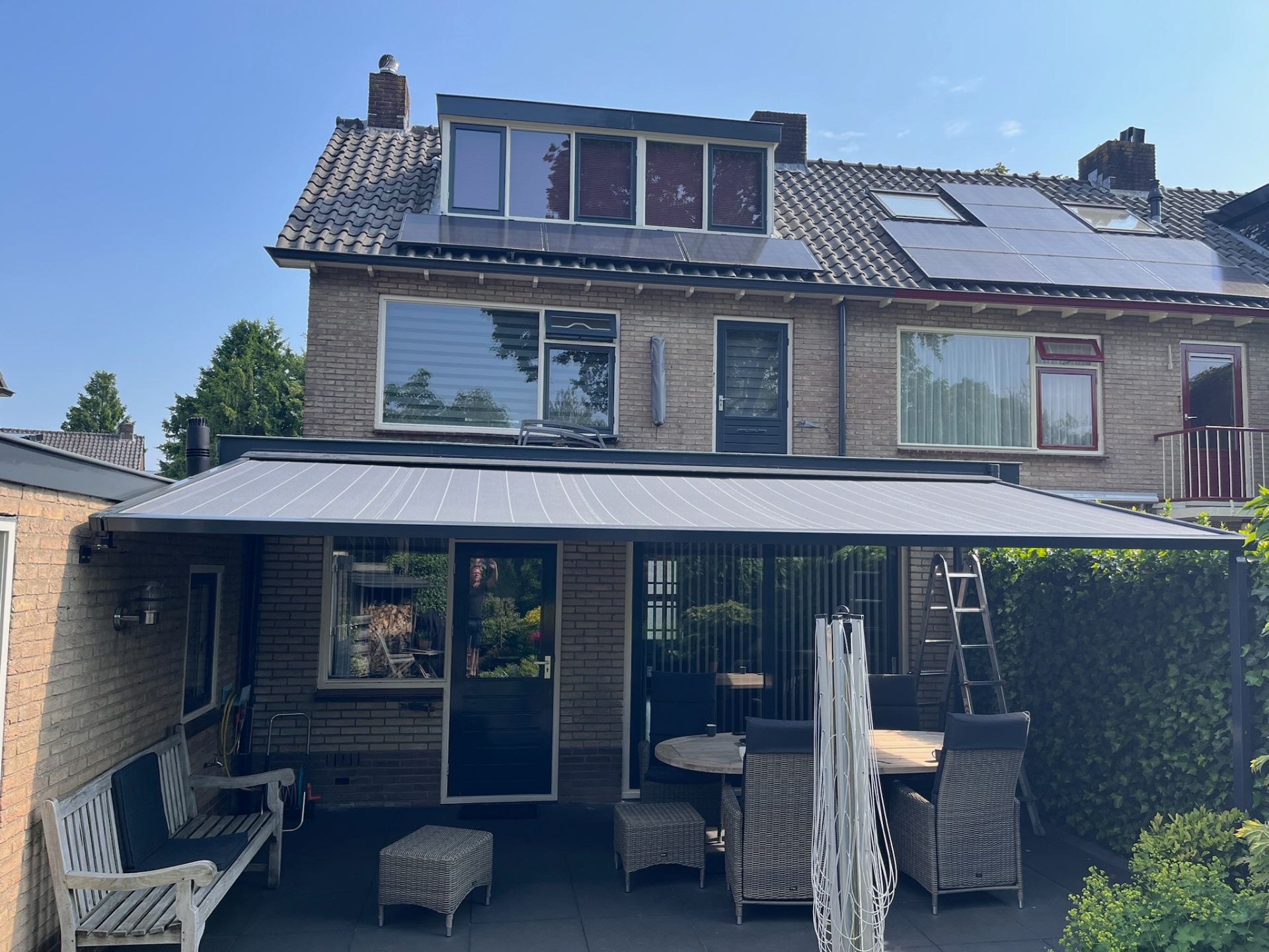 Pergola met grijs doek aan twee-onder-een-kapwoning met loungeset