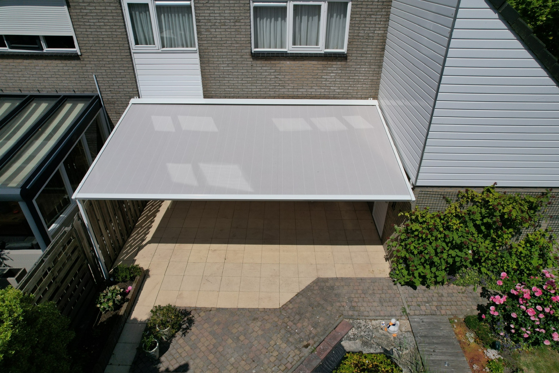 Pergola met wit doek bovenaanzicht boven terras tussen woningen
