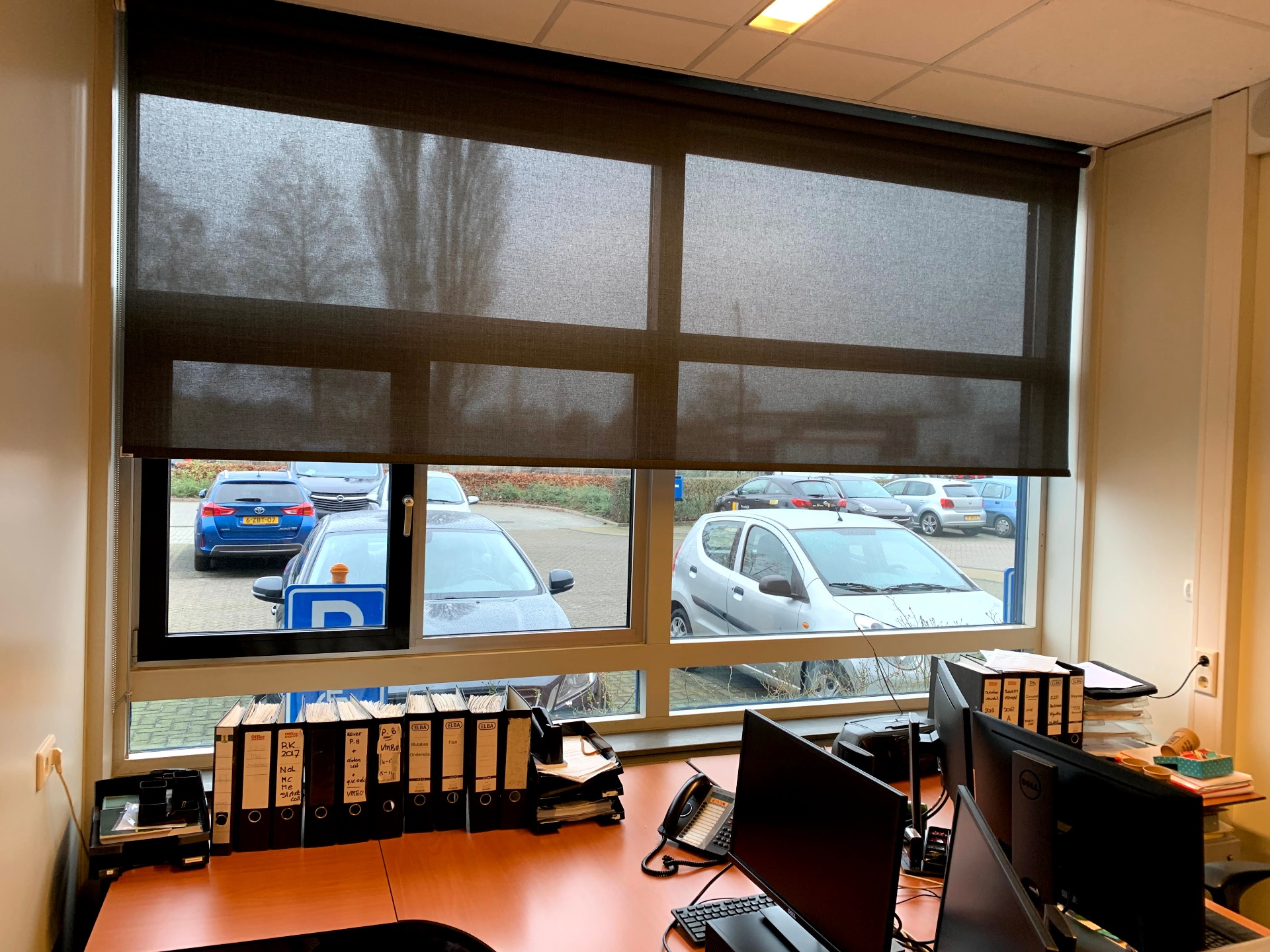 Antraciet screen-rolgordijn in kantoor met behoud van uitzicht