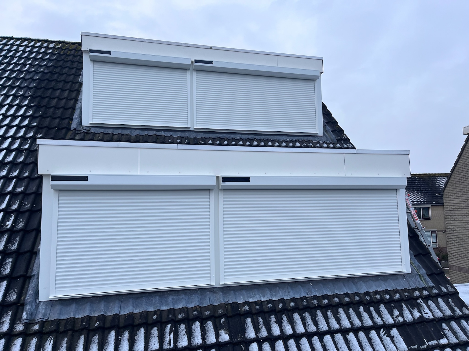 Twee witte solar-rolluiken op twee dakkapellen boven elkaar