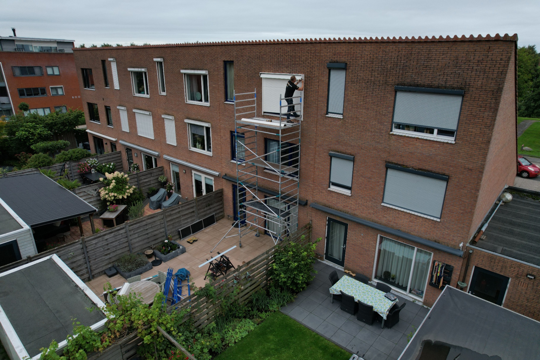 Monteur installeert rolluik op rolsteiger op derde verdieping appartementencomplex
