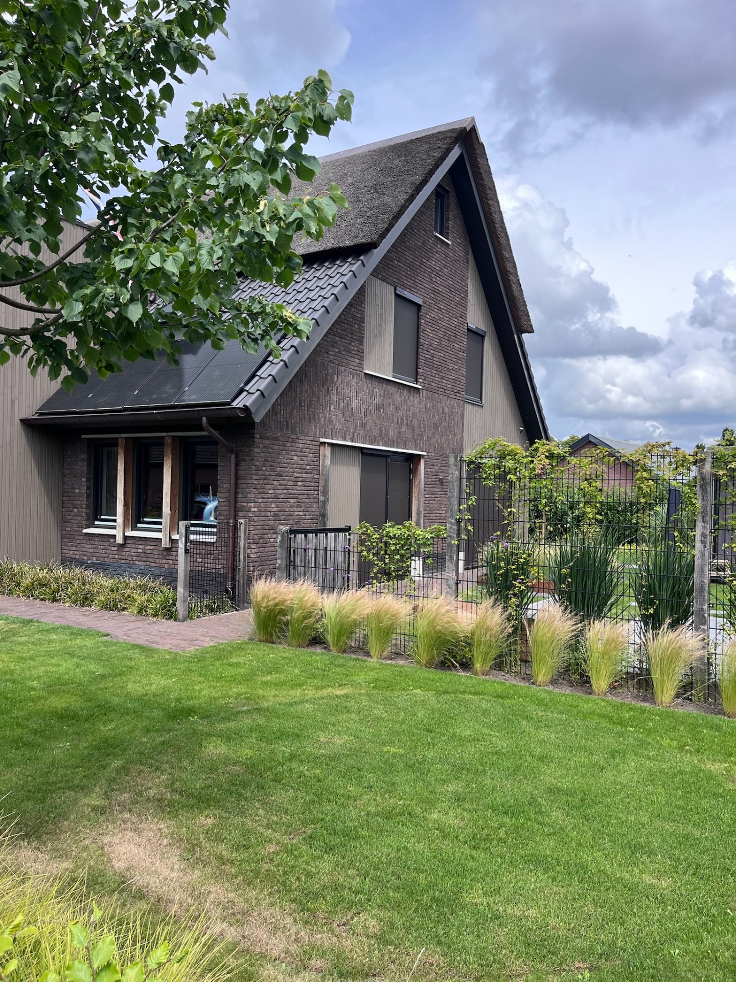 Woning met rieten kap en antraciet screens op bovenverdieping