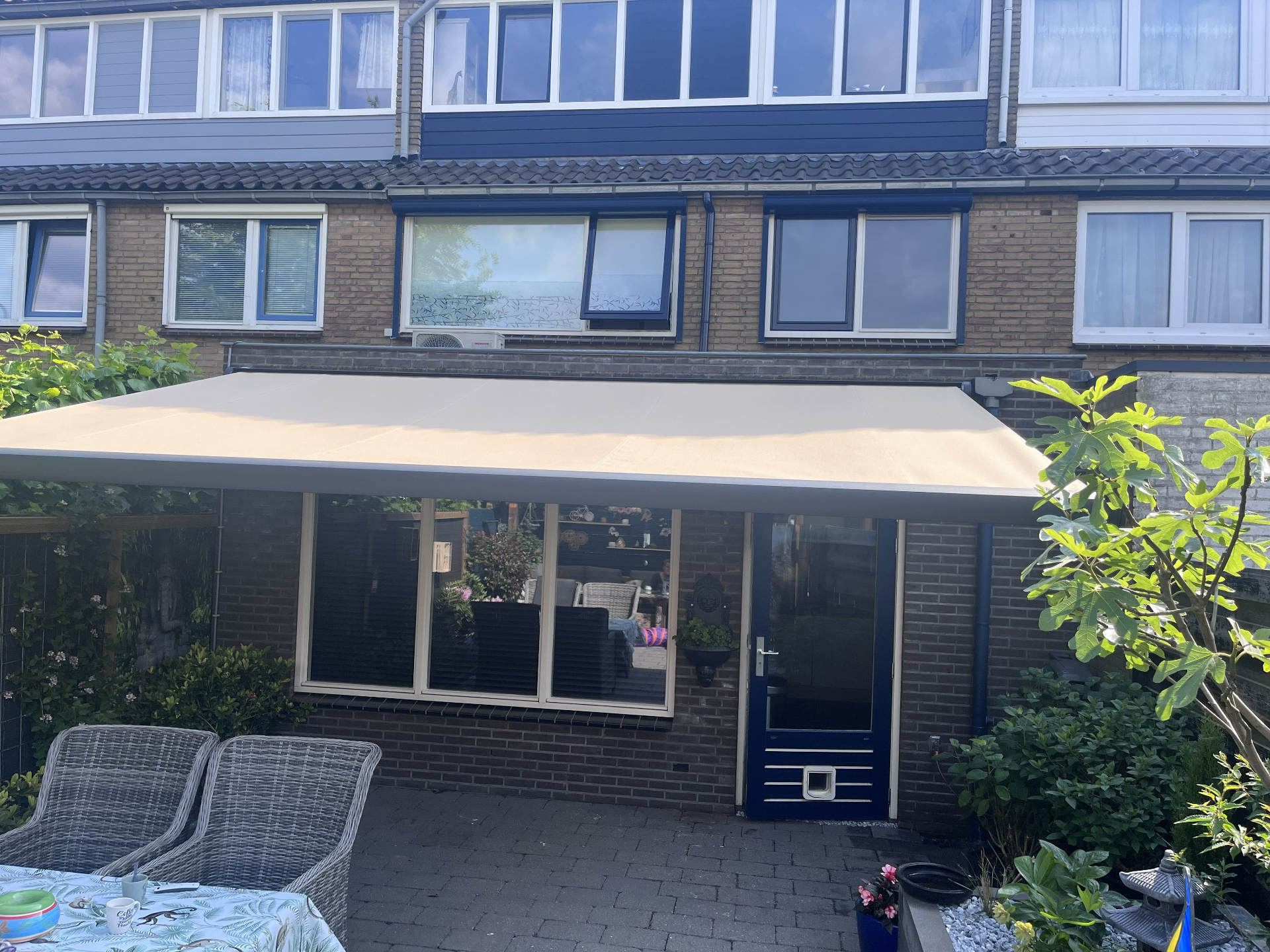Zandkleurig terrasscherm over brede pui van tussenwoning