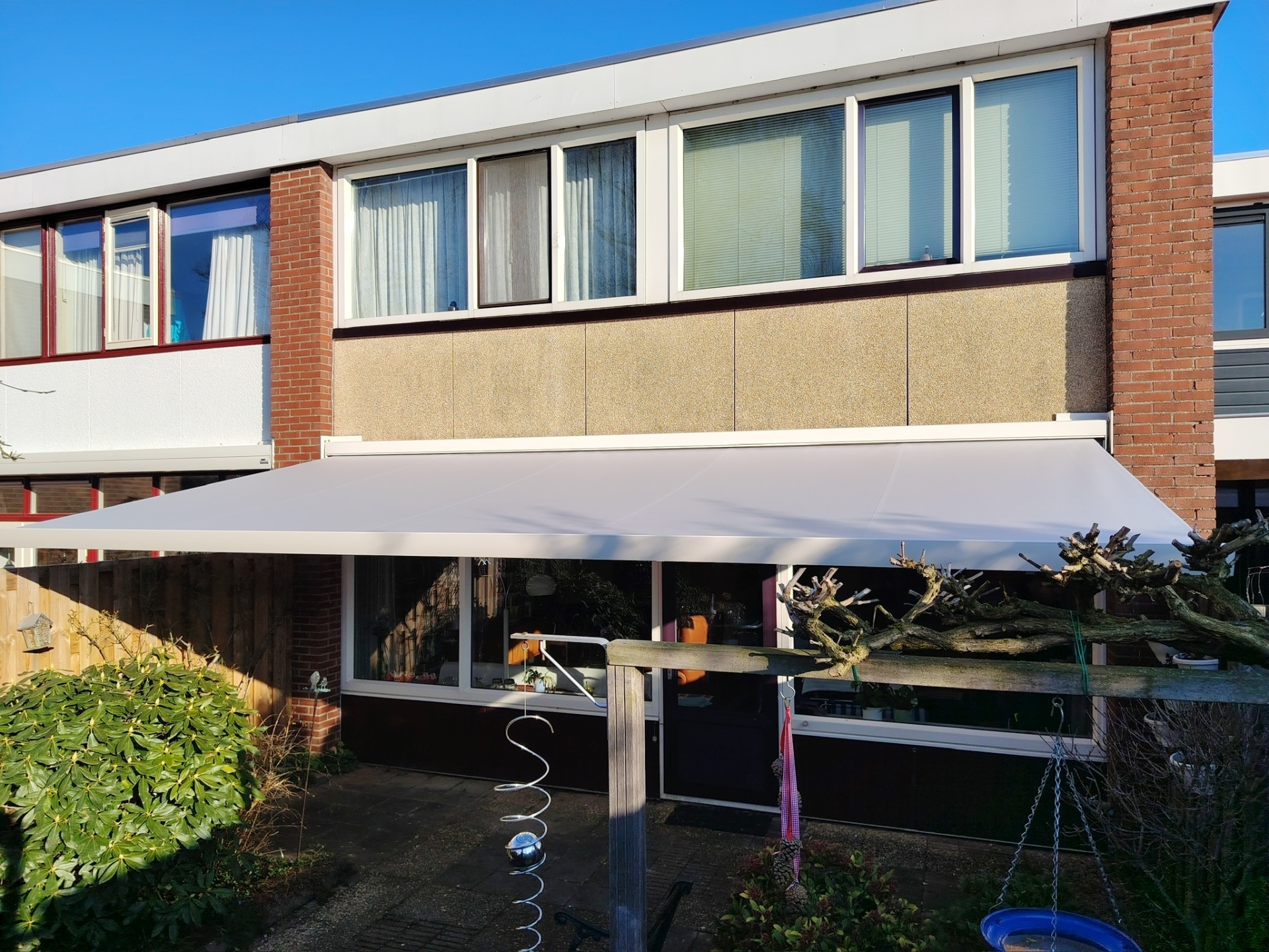 Breed terrasscherm met ivoorkleurig doek aan rijwoning