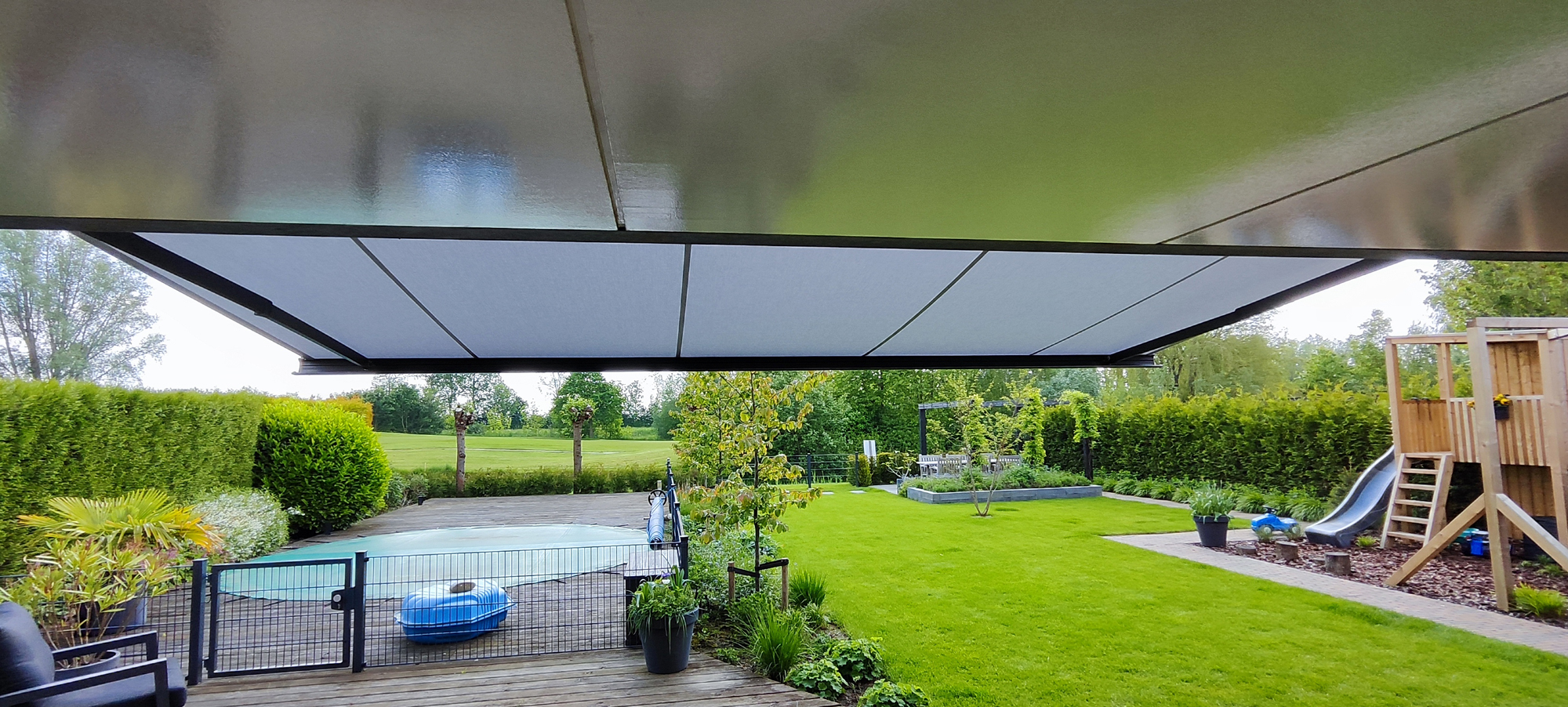 Terrasscherm met groot uitval boven terras en tuin met zwembad