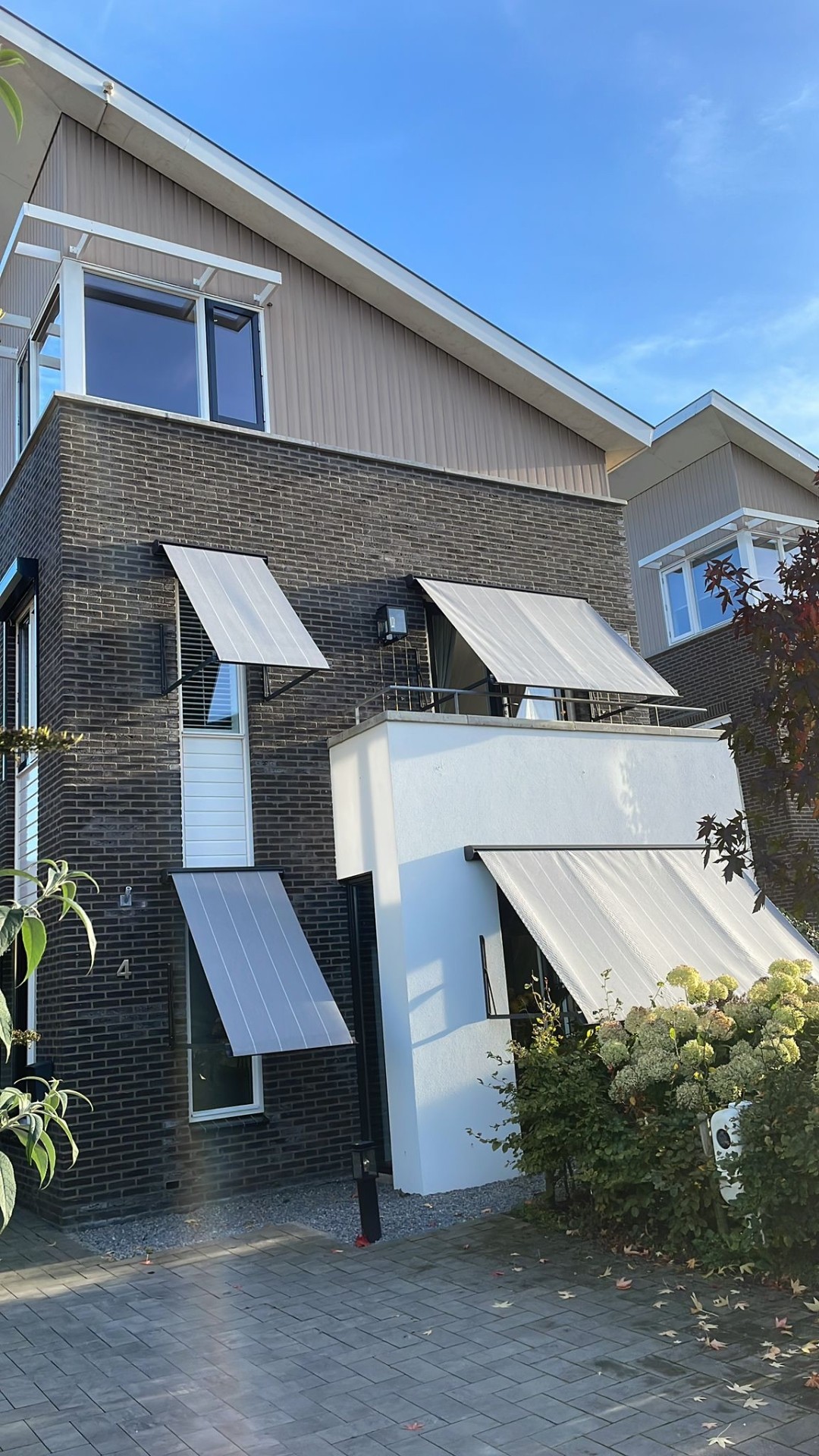 Meerdere uitvalschermen met licht gestreept doek op moderne woning met balkon