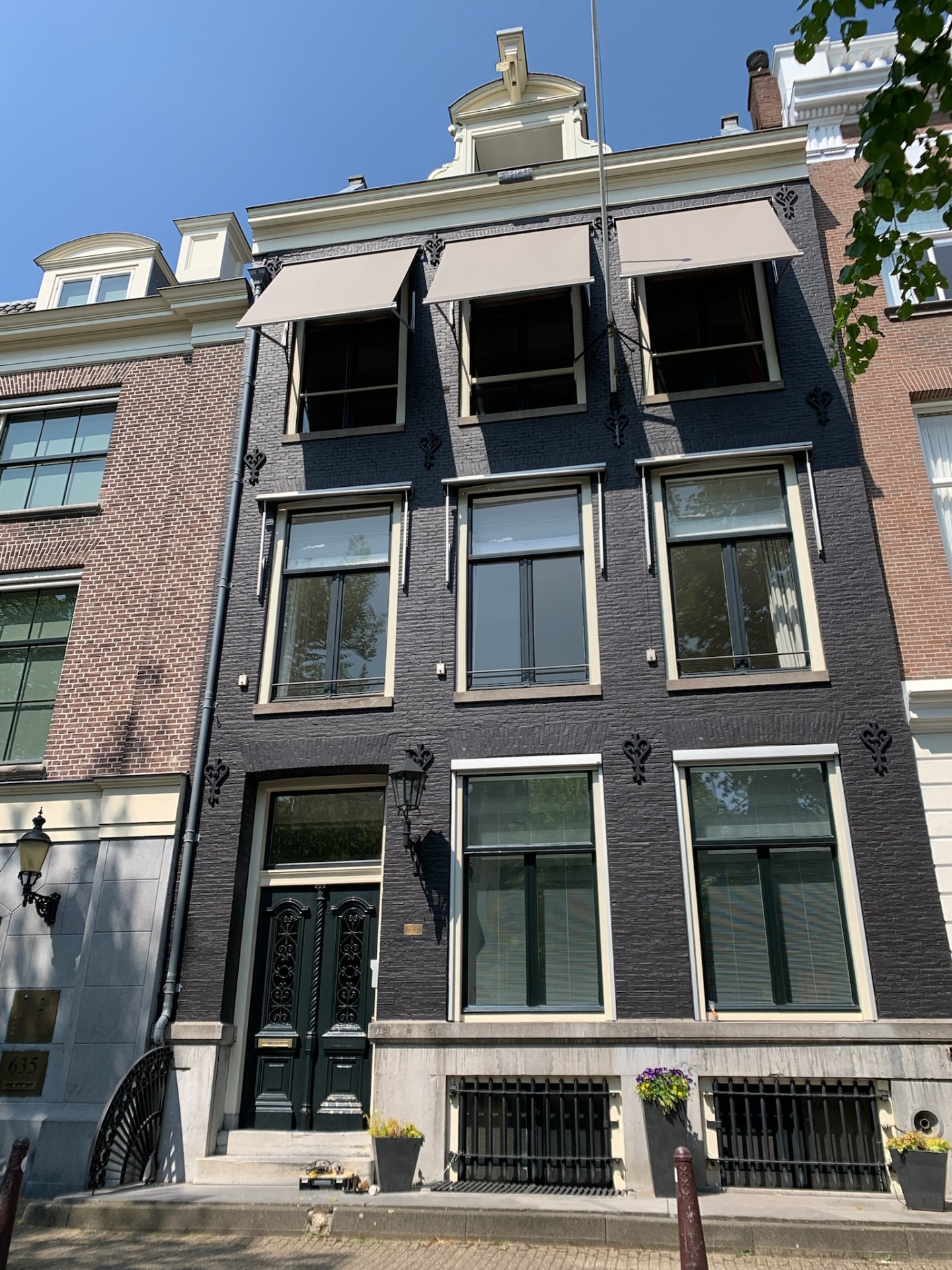 Drie crèmekleurige uitvalschermen op bovenramen van klassiek grachtenpand
