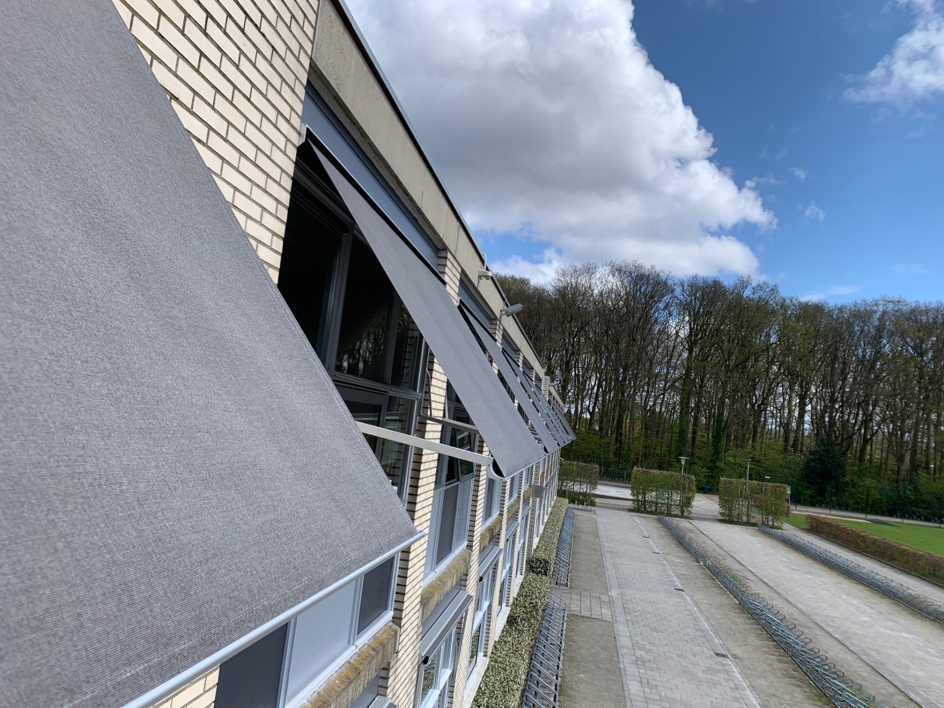 Detail uitvalschermen langs schoolgevel met blauwe lucht