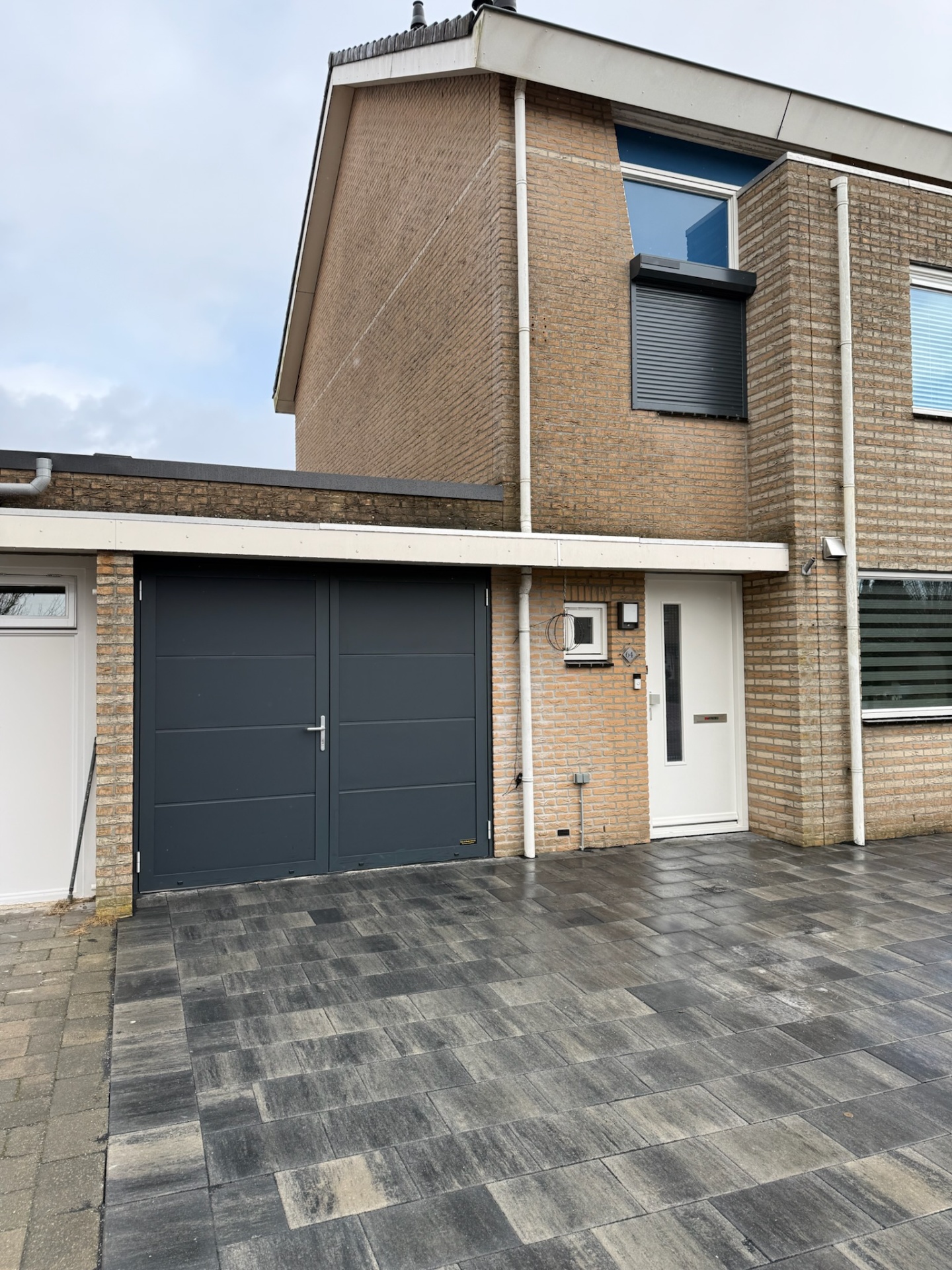 Woning met antraciet garagedeur en rolluik op slaapkamerraam